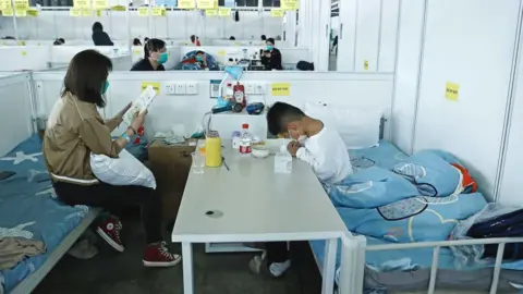 Getty Images A child accompanied by their mother studies while receiving treatment in the quarantine zone at the Shanghai New International Expo Center on April 10, 2022 in Shanghai,