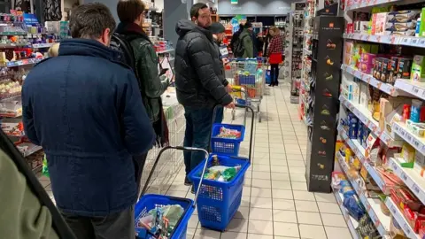 Getty Images People queue to buy food in Milan as quarantine measures are announced