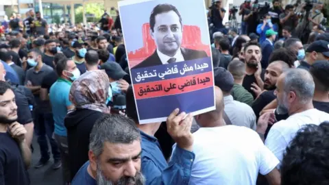 Reuters Hezbollah and Amal supporters hold a poster of Judge Bitar - 14 October