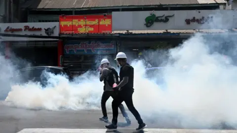 AFP Protesters run after police fired tear gas to disperse them during a demonstration against the military coup in Yangon