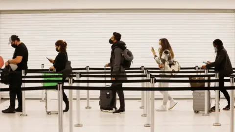 Reuters Passengers queue at arrivals in an airport