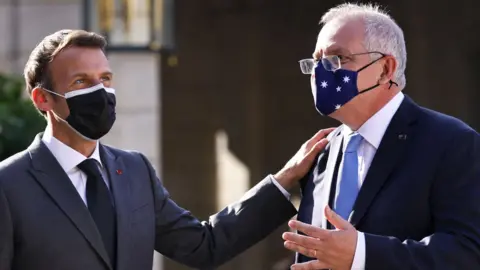 Getty Images French President Emmanuel Macron claps the shoulder of Australia Prime Minister Scott Morrison at a meeting in Paris in June 2021