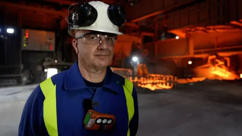 BBC Henrik Adam with steelmaking works behind him