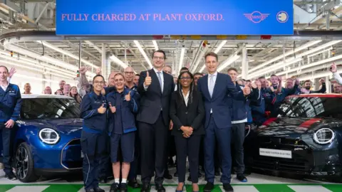 PA Media Trade Secretary Kemi Badenoch (centre) with Dr Milan Nedeljkovic, member of the board of management of BMW AG (left) and Markus Gruneisl, CEO of BMW (UK) Manufacturing, at the Mini plant at Cowley in Oxford