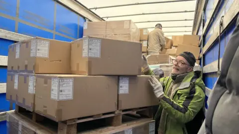 Nicola Haseler/BBC Steve Senior loading a lorry with parcels for Ukraine