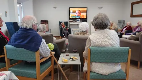 elderly people watching TV in a care home