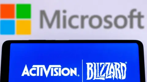 Getty Images Photo illustration of Activision Blizzard logo is displayed on a smartphone screen with a Microsoft Corporation logo in the background.
