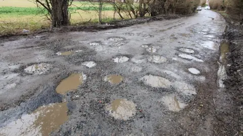 Dawid Wojtowicz/BBC The rural road near Harlow in Essex has many potholes