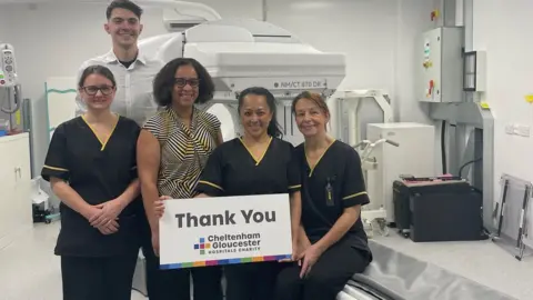 Gloucester Hospitals Charity Hospital staff with a than you sign standing in front of the scanner