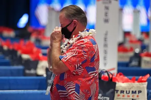 Getty Images A delegate wears a mask and a Hawaiian flag covered in US flags