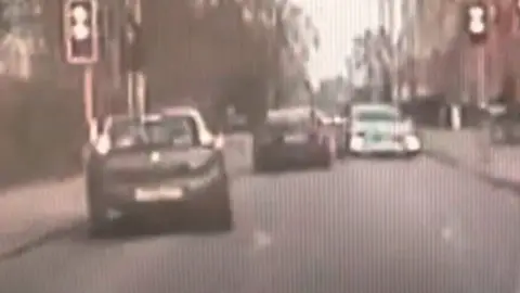 Police dashcam shows a driver narrowly avoiding other cars and bikes while trying to evade officers.