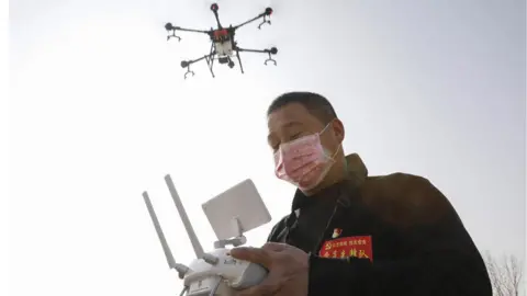 Getty Images A local resident using a drone to spray disinfectant in China