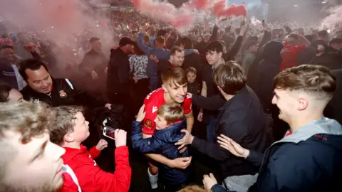 Reuters Wrexham's Max Cleworth celebrates with fans on the pitch after the match