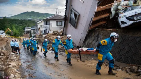 AFP Police arrive to clear debris scattered on a street in a flood hit area in Kumano