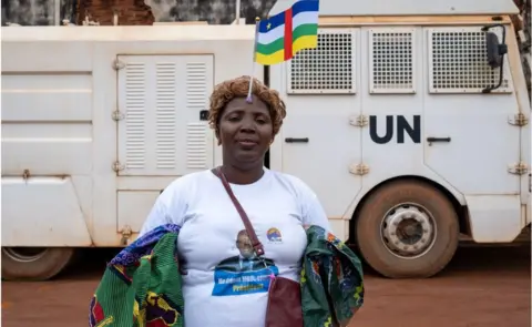 AFP Woman with CAR flag on her head wearing a T-shirt with the face on Crepin Mbouli Goumba on it.