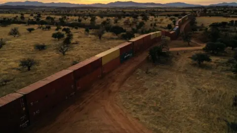 A long fence made up of stacked containers