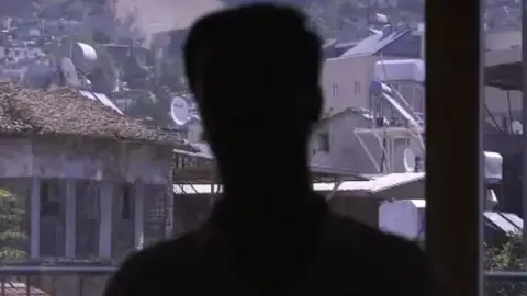 BBC A screengrab from the BBC documentary Syria: The World's War, showing a man's head in silhouette