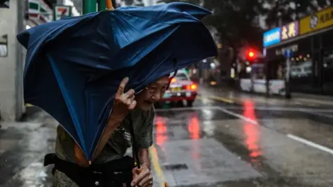 AFP An elderly man man struggles with an umbrella in a Hong Kong city street