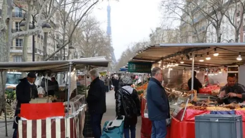 AFP People shop at an open air market in Paris on March 21, 2020