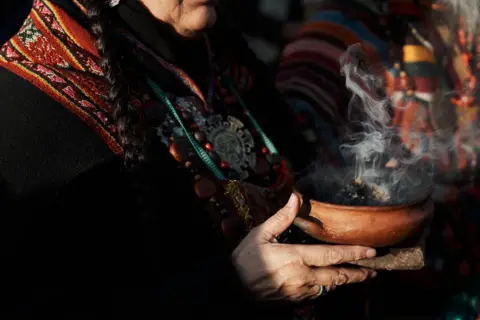 NATALIA FAVRE A woman smokes aromatic herbs during a ceremony for Pachamama in Buenos Aires, Argentina, where members of more than 400 indigenous communities arrived after traveling more than 1800 kilometres to protest against the constitutional reform of the governor of Jujuy, on August 1, 2023.