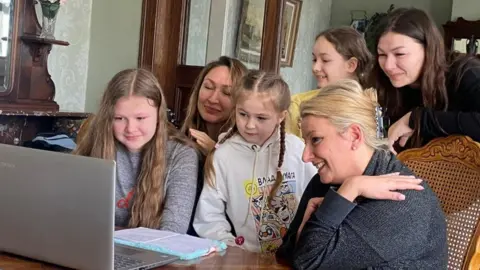 The family crowd around a computer to speak to the BBC