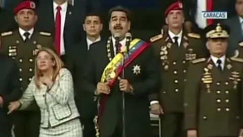 Reuters President Maduro (centre) and his wife Cilia Flores (left) react to a loud bang during the military event