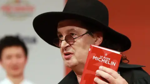 Getty Images French chef Marc Veyrat, holds a Michelin guide after being awarded the maximum three Michelin stars at La Seine Musicale in Boulogne-Billancourt near Paris, 5 February 2018