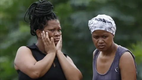 Neighbours watch as rescuers and sniffer dogs search for 10 missing people in KwaNdengezi township, near Durban, on 15 April.