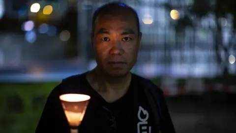 BBC / Wei Wang Lam Wing Kong holds a candle