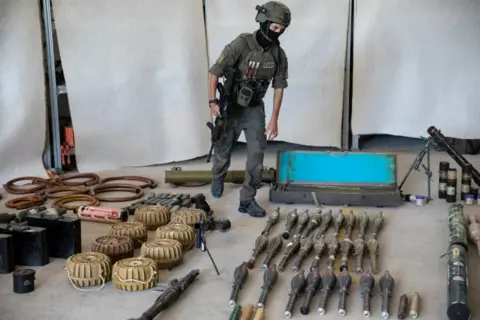 Getty Images An Israeli soldier stands with grenades, rocket launchers and other military equipment and ammunition that Hamas and Palestinans militants used in their attack on Israel