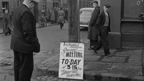 Bert Hardy/GETTY IMAGES Man looking at a poster for a meeting about unemployment in Derry