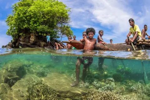 Morgan Bennett-Smith A group of adults and children in the waters near mangrove trees