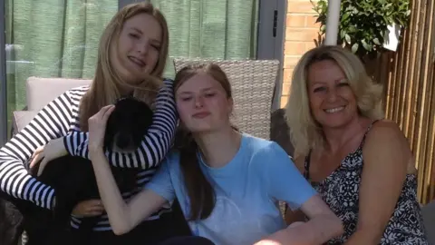 Louise Drake Louise Drake and her two daughters, with a dog in the foreground