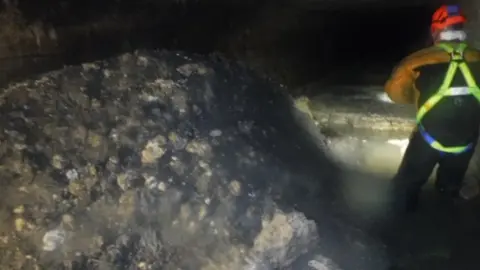 South West Water A sewer worker stands next to the "monster" fatberg