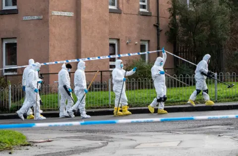 PA Media Forensic officers searching scene