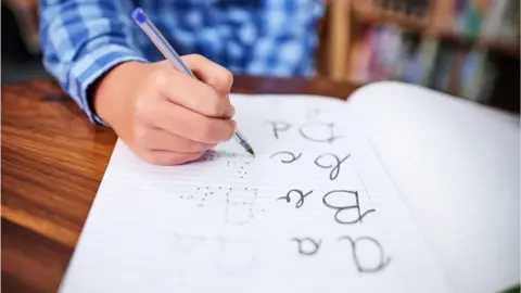 Getty Images Boy's hand writing in exercise book