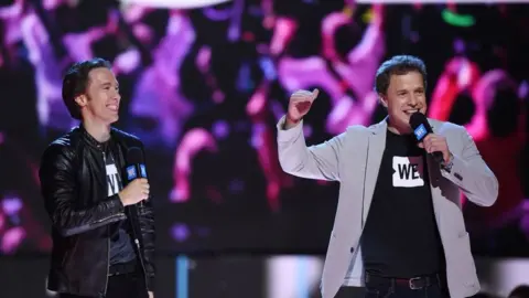 AFP via Getty Images WE co-founders Craig Kielburger and Marc Kielburger speak on stage at WE Day California, April 27, 2017