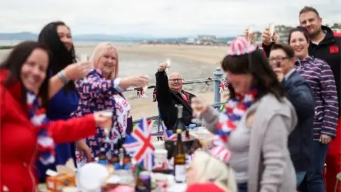 Reuters A man raises his glass as people attend the Morecambe Town Council street party amid celebrations