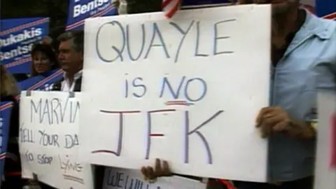 Person holds sign against Dan Quayle