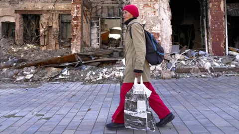 Getty Images A woman walks past the damaged area after clashes are occurred as Russia-Ukraine war continues in Mariupol, Donetsk Oblast, Ukraine on September 29, 2022.