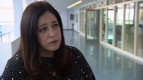 Haringey Council Leader Councillor Peray Ahmet, wearing a spotted dress and standing on a school landing