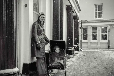 Michael Bennett Person with a child in a pushchair outdoors, in Conwy