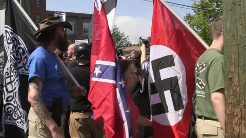 Getty Images Demonstrators carry confederate and Nazi flags during the Unite the Right free speech rally at Emancipation Park in Charlottesville, Virginia, on August 12, 2017