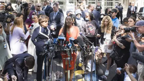 EPA Jovante Cunningham (C), one of the women who have accused R. Kelly of sexual abuse, with attorney Gloria Allred (C-R) at a press conference outside of the United States Courthouse after the former R^B singer was sentenced to 30 years in prison after his conviction last year on federal racketeering and sex trafficking charges in the Brooklyn borough of New York,