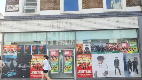 A woman walks past an empty shop on Oxford Street