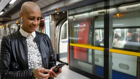 TfL Woman looking at her phone on a Tube platform