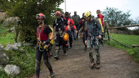 EPA Members of Spanish rescue services escort four missing Portuguese men who were rescued after being trapped at a cave in Arredondo