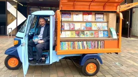Portsmouth City Council Councillor Steve Pitt, leader of the council, posing in the Tuk-tuk outside central library