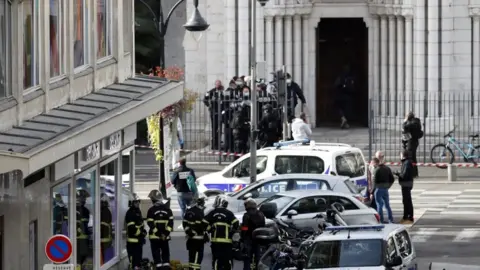 EPA French police officers stand at the entrance of the Notre Dame Basilica church in Nice, France, 29 October 2020