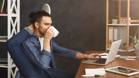 Getty Images Man in yoga position at work